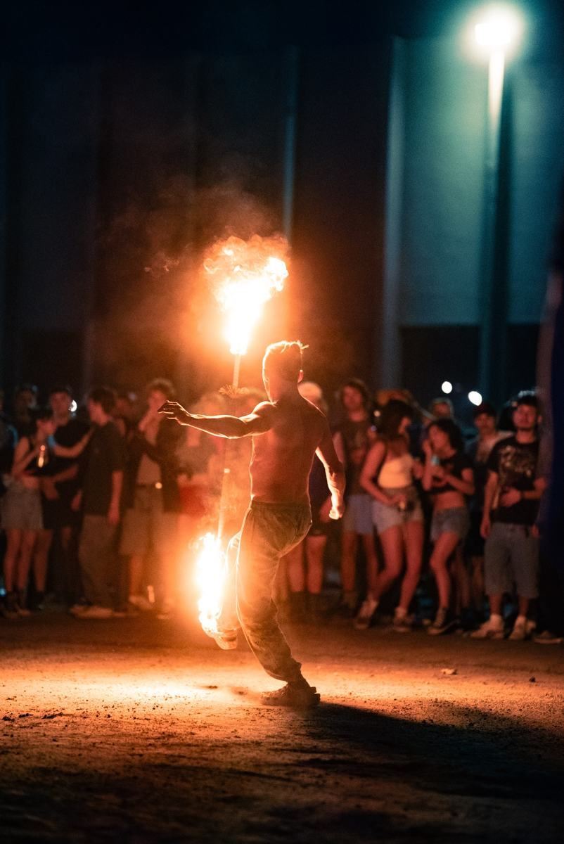 Tyler backlit by a fire staff in front of a crowd at night