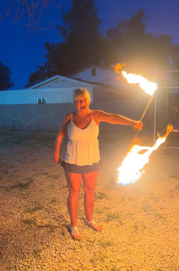 A first-time spinner laughing with joy while holding a burning fire staff