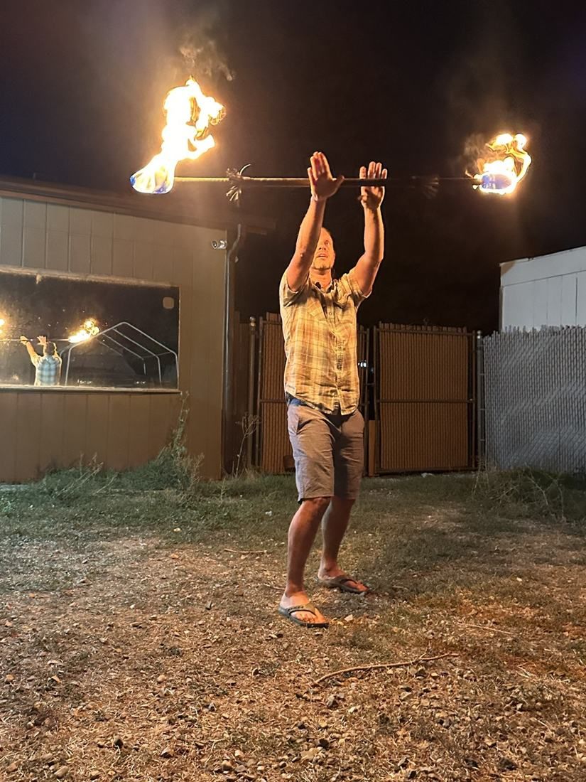 A man balancing a burning fire staff overhead