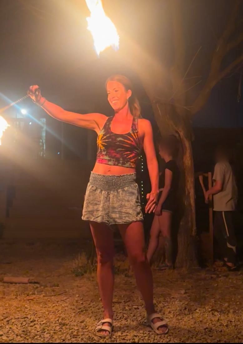 A smiling woman spinning fire for the first time